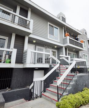 Van Nuys apartment for rent - A grey building with a black railing and a red staircase.