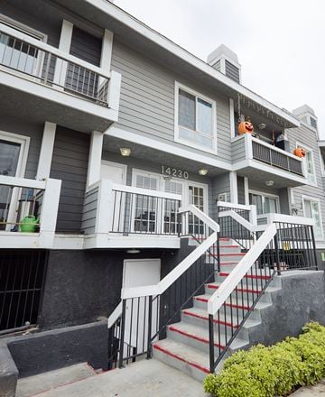 Van Nuys apartment for rent - A grey building with a black railing and a red staircase.