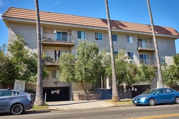 Los Angeles apartment for rent - A blue car is parked in front of a building with a brown roof.