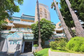Los Angeles apartment for rent - A Marta Palms building with a green sign and palm trees in front.