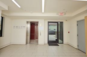 North Hollywood apartment for rent - A white hallway with a red exit sign above the door.