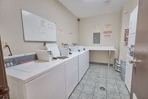 Los Angeles apartment for rent - A laundromat with a white dryer and washer, a white ironing board, and a white sink.