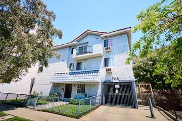 Los Angeles apartment for rent - A white house with a red tile roof and a black gate.