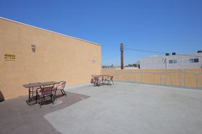 Los Angeles apartment for rent - A patio with a table and chairs is in front of a tan wall.