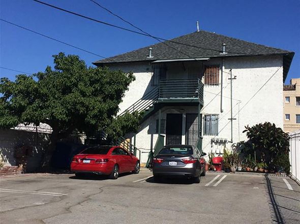Los Angeles apartment for rent - Two cars parked in front of a white building with a black roof.