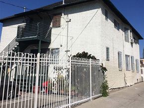 Los Angeles apartment for rent - A white building with a green railing and a white fence.