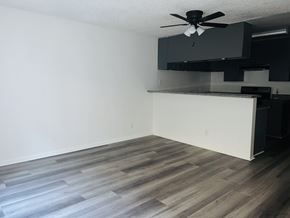 Los Angeles apartment for rent - A room with a ceiling fan and a kitchen area with black cabinets.