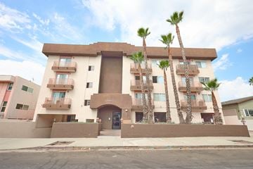 Los Angeles apartment for rent - A building with a brown facade and palm trees in front.