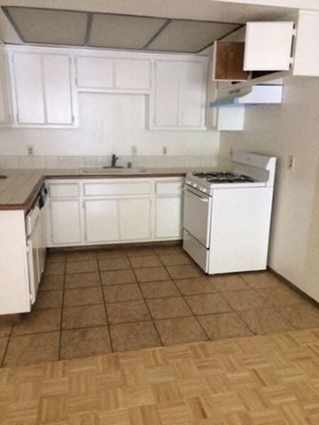Los Angeles apartment for rent - an empty kitchen with white cabinets and a stove