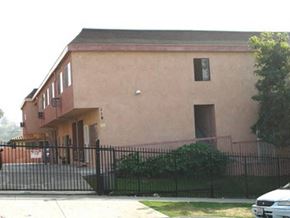 Los Angeles apartment for rent - a large building with a fence and a car parked in front of it