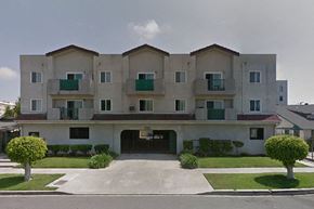 Los Angeles apartment for rent - a white apartment building with green balconies and a driveway
