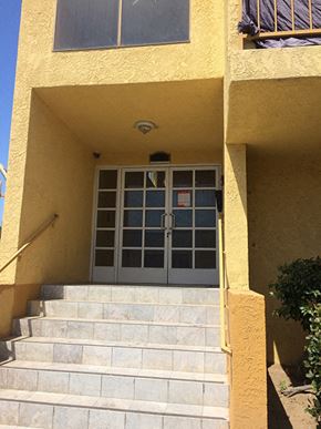 San Pedro apartment for rent - the front door of a yellow building with stairs in front of it