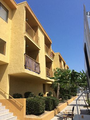 San Pedro apartment for rent - a row of yellow apartments with balconies and bushes