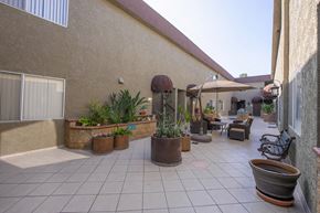 Canoga Park apartment for rent - a patio with tables and chairs and potted plants