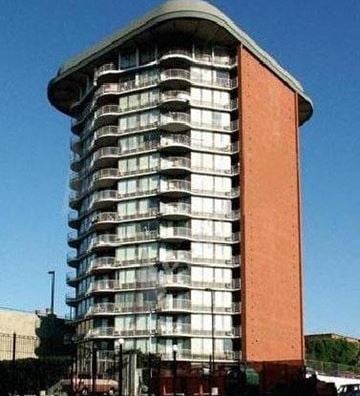 Spokane apartment for rent - A tall building with a curved top and a red section on the side.