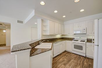 A kitchen with white cabinets and granite countertops