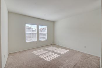 A bedroom with two windows and a carpeted floor