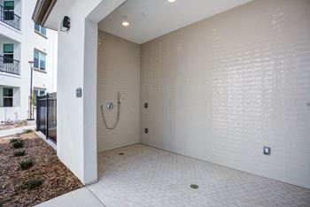 A white tiled bathroom with a shower and a toilet.