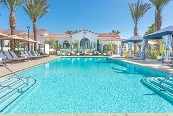 A resort style swimming pool with lounge chairs and umbrellas