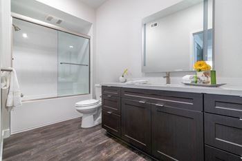 A bathroom with white walls and a wooden floor