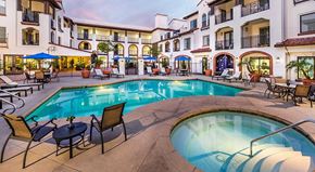 Laguna Woods apartment for rent - A large outdoor pool area with chairs and a hot tub at a resort.