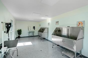 A room with two large stainless steel sinks and a table and chairs