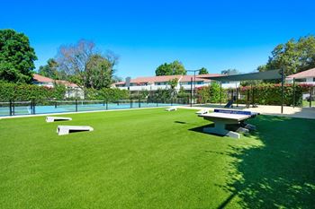 A picnic table and ping pong table sit in the middle of a grassy area