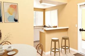 Lake Forest apartment for rent - A kitchen with a bar stool and a table with a vase and a plate on it.