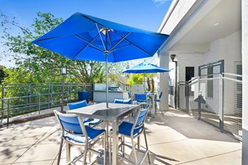 A patio with blue umbrellas and a dining table with blue chairs