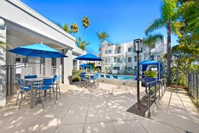 San Diego apartment for rent - a patio with blue chairs and umbrellas and a swimming pool at Nobel Court, San Diego, CA
