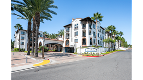 Laguna Woods apartment for rent - A street view of a building with palm trees in front.