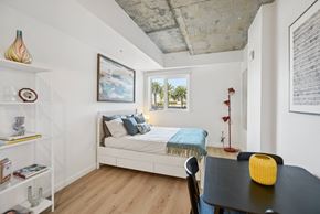 Santa Monica apartment for rent - A new studio bedroom with a bed, a table, and a chair.  Palm trees are in the window.
