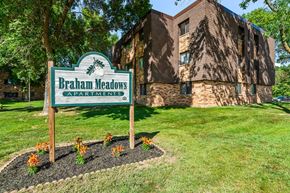 Braham apartment for rent - A sign for Braham Meadows Apartments stands in front of a brick building.