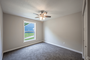 Stillwater apartment for rent - A room with a ceiling fan and a window overlooking a blue fence.
