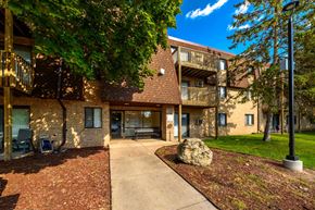 Oakdale apartment for rent - A large rock sits in the middle of a grassy area in front of a building.
