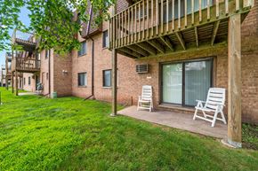 Oakdale apartment for rent - A balcony with two chairs and a table is on the right side of a brick building.
