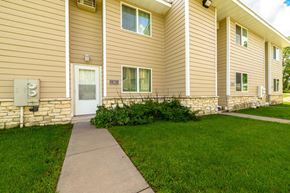 Oakdale townhouse for rent - A building with a brown siding and a white door with windows on the side.