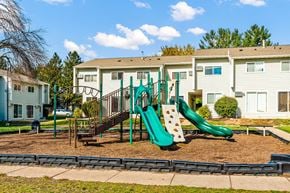 Faribault townhouse for rent - A playground with a green slide and a brown swing set.