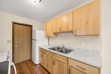 Faribault townhouse for rent - A kitchen with wooden cabinets and a white fridge.