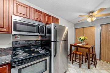 Forest Lake apartment for rent - A kitchen with a stove, microwave, refrigerator, and a table with chairs.