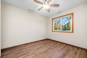 Forest Lake townhouse for rent - A room with a ceiling fan and a window showing a tree and a building outside.