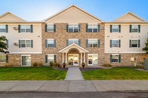 Forest Lake apartment for rent - A large apartment building with a front entrance and a walkway leading to it.