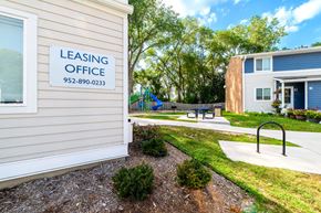 Burnsville townhouse for rent - A leasing office sign is on a building with a playground in the background.