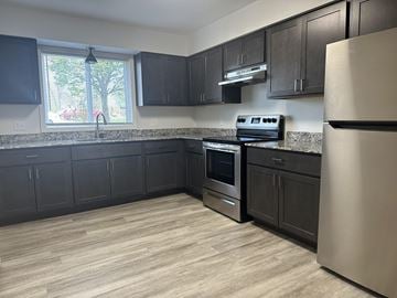 Owatonna apartment for rent - A kitchen with black cabinets and a stainless steel refrigerator.