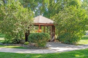 Forest Lake apartment for rent - a gazebo in a garden with trees and a sidewalk