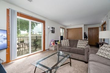 Forest Lake apartment for rent - A living room with a glass coffee table and a grey couch.