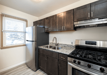 Owatonna apartment for rent - A kitchen with a stainless steel refrigerator, sink, and stove.