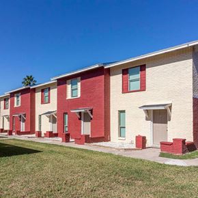 Harlingen apartment for rent - A row of red and white houses with green lawns in front.