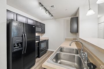 Knoxville apartment for rent - A black fridge and oven in a kitchen with a stainless steel sink.