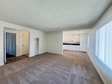 Tustin apartment for rent - A spacious living room with a patterned carpet and a kitchen in the background.